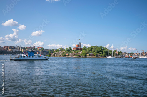 The inner harbor passenger ferry Djurgårdsfärjan, in the bay Ladugårdslandsviken, the castell on the island Kastellholmen, a sunny summer morning in Stockholm