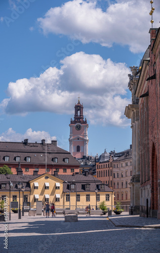 Old houses and the tower of the church Storkyrkan, a square at the island Riddarholmen, a sunny summer day in Stockholm