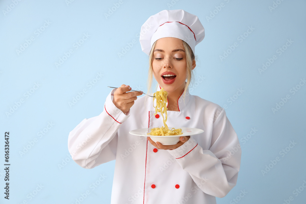 Female chef eating tasty pasta on blue background Female chef eating tasty pasta on blue background