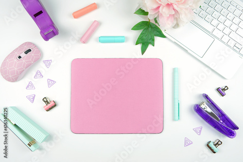 Pink mouse pad mockup. Styled with computer keyboard and modern desktop accessories. Negative copy space.