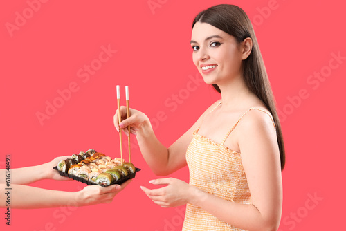 Young woman taking sushi on...