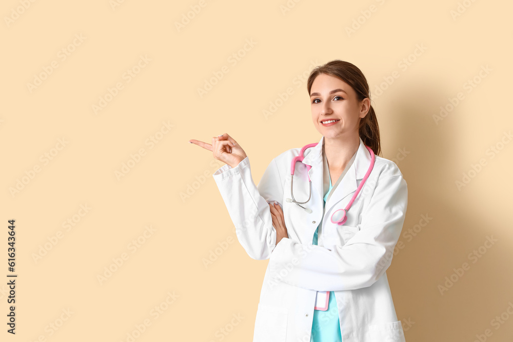 Female medical intern pointing at something on beige background Female medical intern pointing at something on beige background