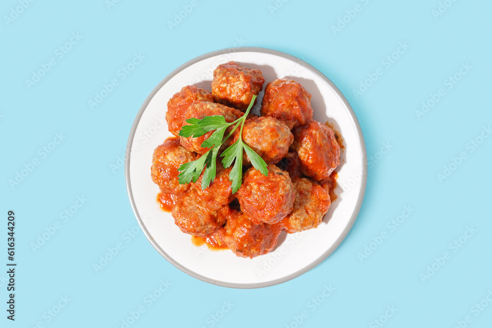 Plate of tasty meat balls with sauce on blue background Plate of tasty meat balls with sauce on blue background
