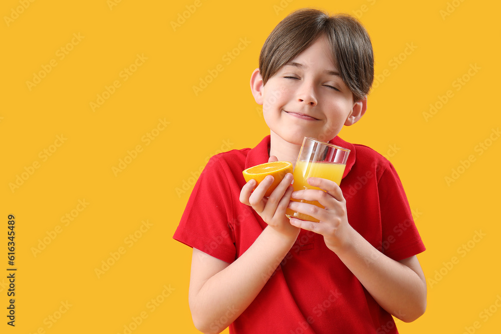 Little boy with orange and glass of juice on color background