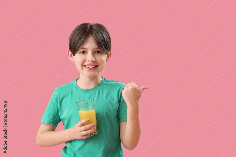 Little boy with glass of orange juice pointing at something on pink background Little boy with glass of orange juice pointing at something on pink background