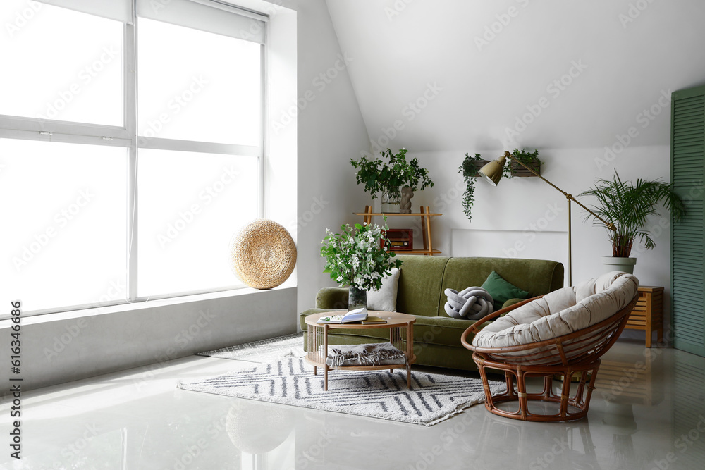 Interior of light living room with green sofa and blooming jasmine flowers on coffee table Interior of light living room with green sofa and blooming jasmine flowers on coffee table