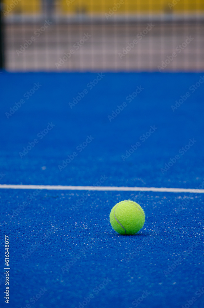 a paddle tennis ball on a blue artificial grass court, racket sports concept
