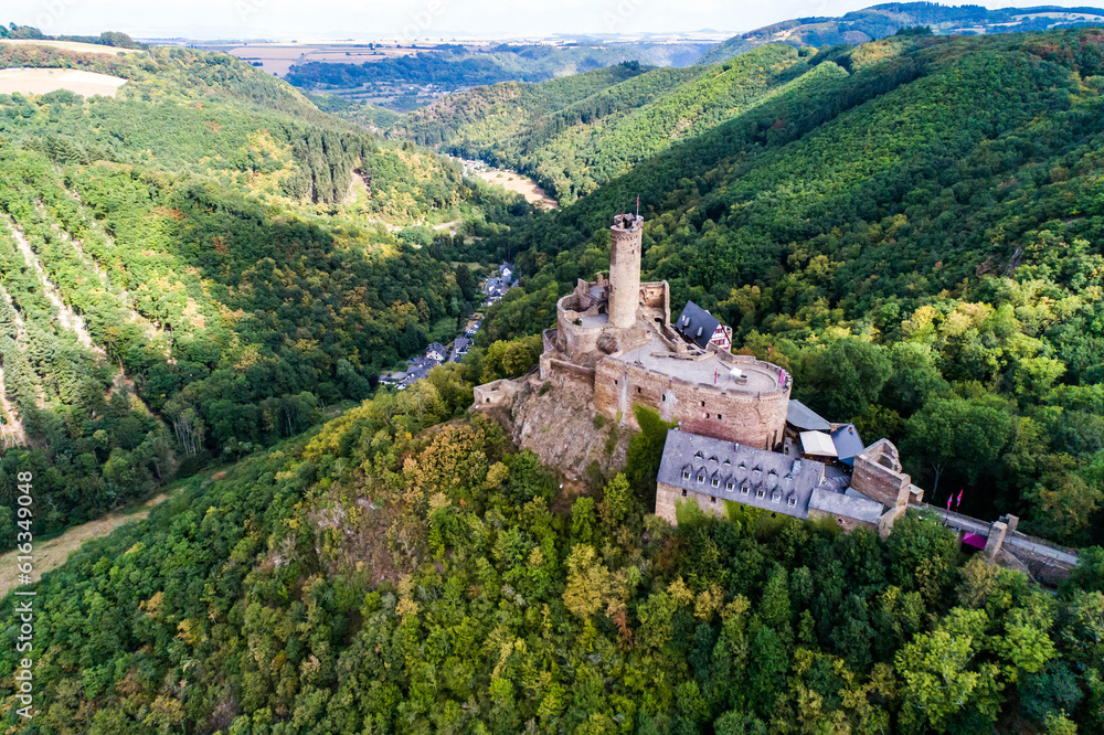 aerial view rock with medieval castle Ehrenburg on it near moselle river in Brodenbach with forest hills