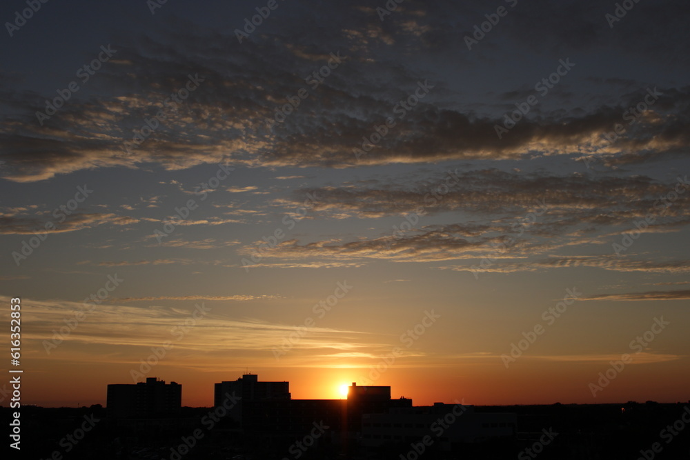 The sky and clouds at sunset on the background of the city line