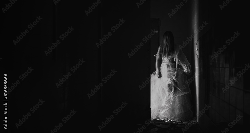 Horror scene of a possessed zombie bride, woman in white dress ghost holding dried roses in dark room. Halloween scary concept