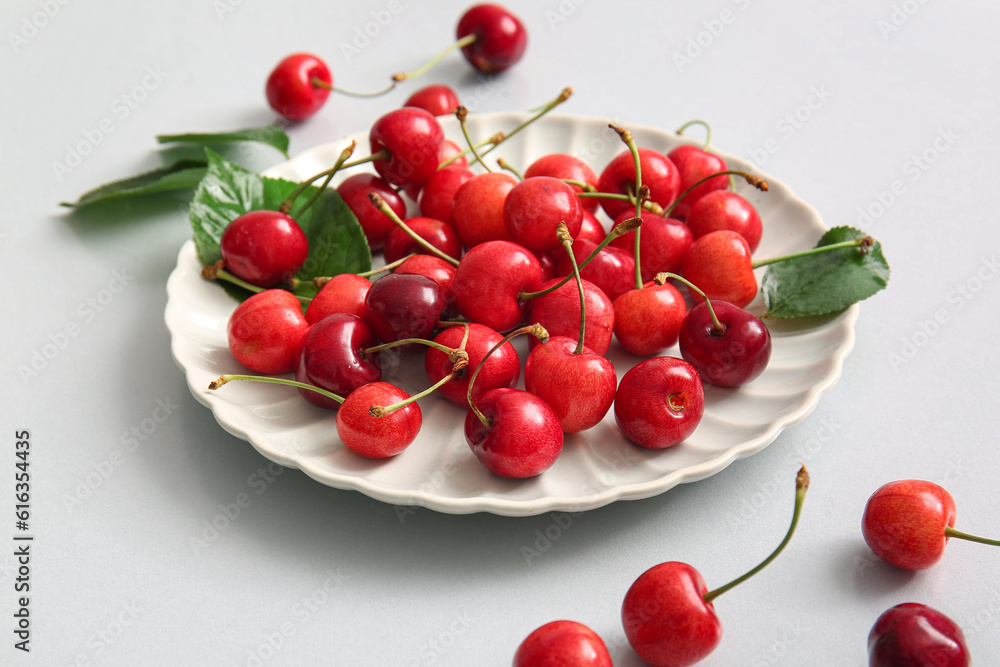 Plate with sweet cherries and leaves on white background Plate with sweet cherries and leaves on white background