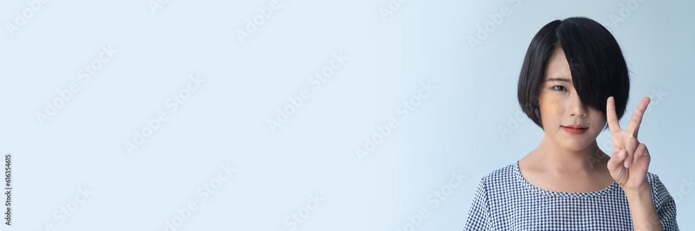 Happy smiling asian woman with short hair pointing up two fingers, v for victory Happy smiling asian woman with short hair pointing up two fingers, v for victory