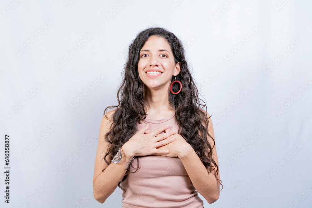 Positive woman with lovely sincere smile feeling thankful, relaxed person showing thank you gesture with hands on chest, Grateful people concept Positive woman with lovely sincere smile feeling thankful, relaxed person showing thank you gesture with hands on chest, Grateful people concept