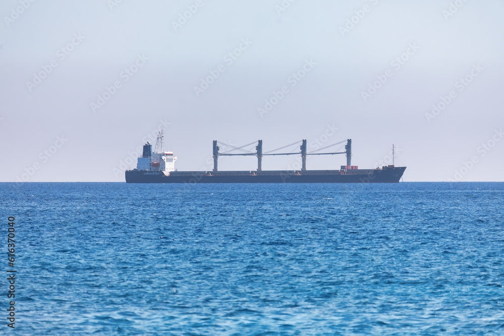 Cargo ship in the sea on a background of blue sky. Large ship in the middle of the ocean 
