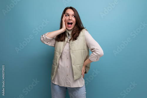 positive young brunette lady showing inspiration with hand on studio background with copy space