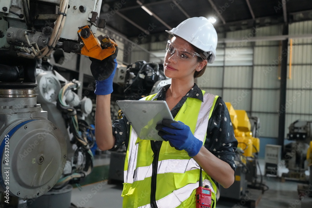 Fototapeta premium Woman working intently on a complicated industry 4.0 robot plant in technology factory.