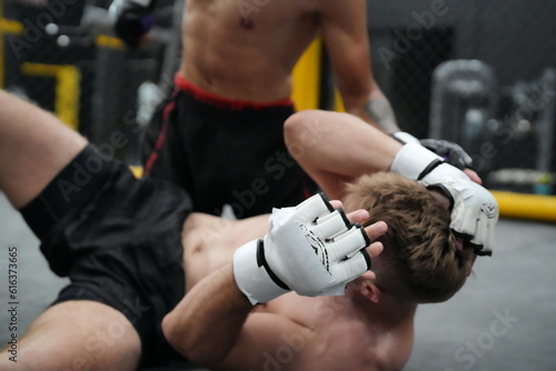 Foto MMA Fight Takedown: Two mixed martial arts fighters locked in a ground struggle, one attempting a takedown while the other defends, showcasing the intensity and physicality of the sport