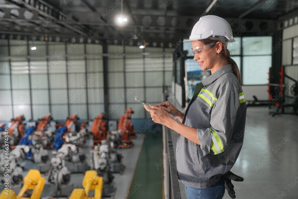 Portrait of Female Automotive Industry 4.0 Engineer in Safety Uniform Using Laptop at Car Factory Facility. Assembly Plant. engineer working at automated AI robotic production factory.. Portrait of Female Automotive Industry 4.0 Engineer in Safety Uniform Using Laptop at Car Factory Facility. Assembly Plant. engineer working at automated AI robotic production factory..