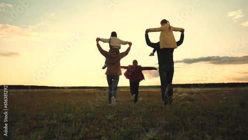 happy family jogging at sunset. group people child mother father run glare sun. family outdoors garden having fun. father mother carry smile children shoulders. summer holidays. running daughter son