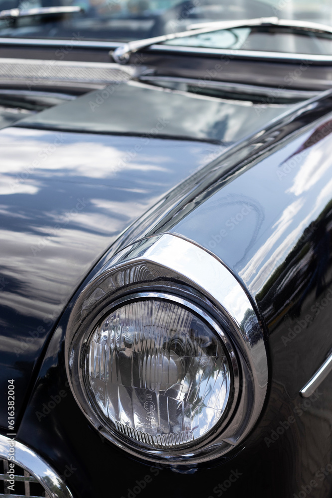 Chrome headlight on a black retro car. Close-up.