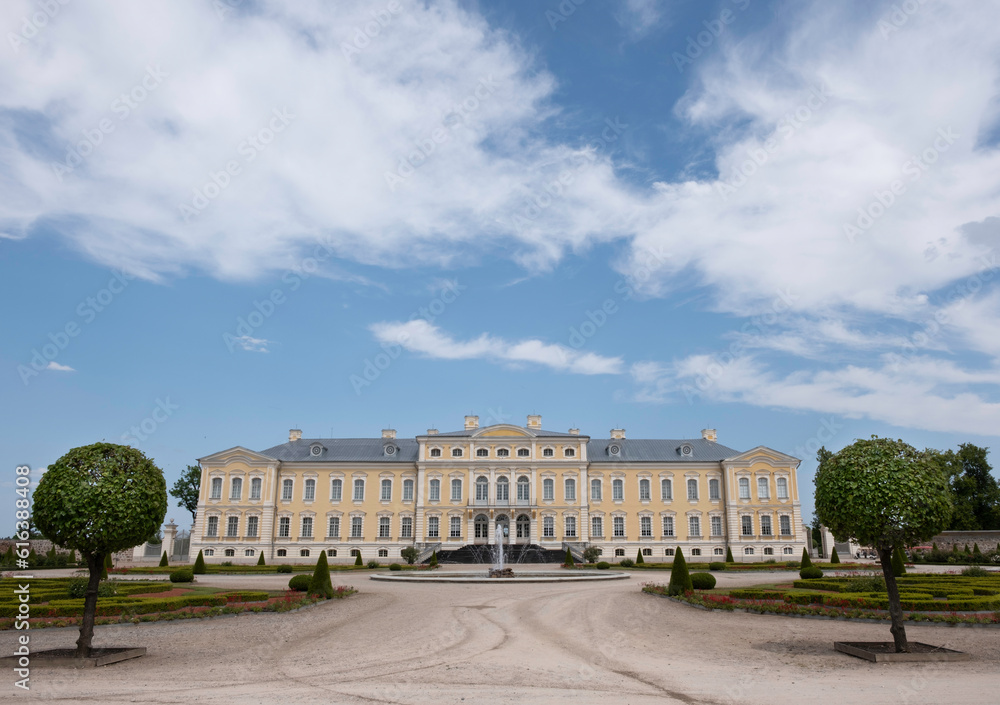 Rundale Palace in the Bauska Municipality in Latvia. Baroque yellow building in a park. Blue sky with clouds