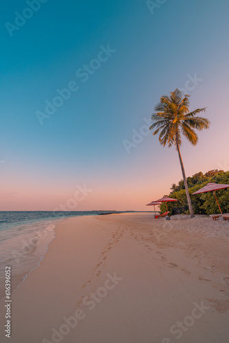 Beautiful tropical sunset. Couple sun beds, loungers, umbrella under palm trees. Sand coast sea view with horizon, colorful romantic sky, calm peace love relax. Leisure beach resort amazing landscape