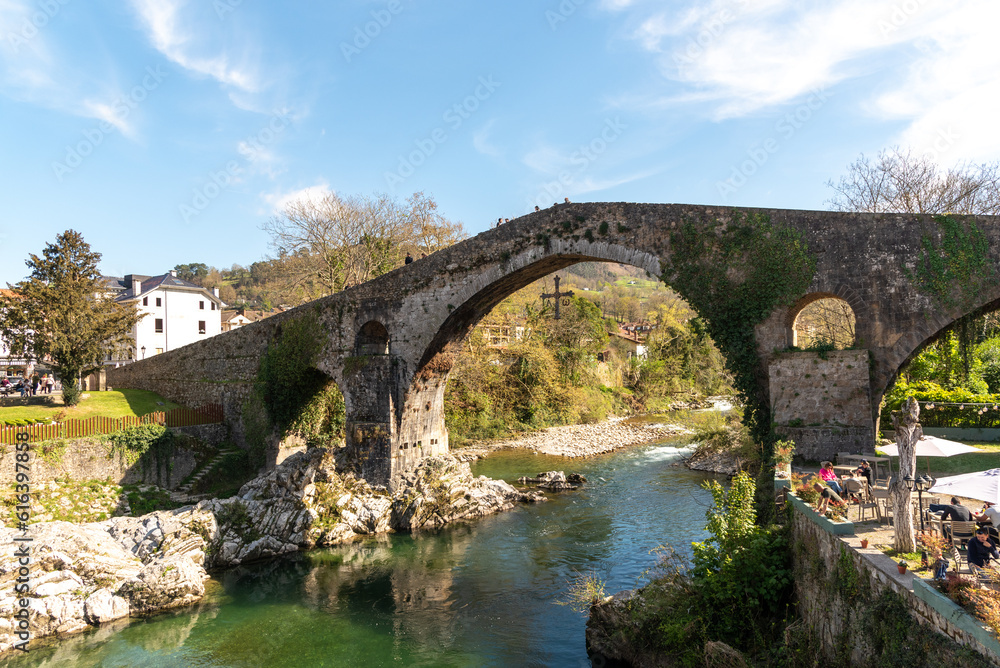 Impressive view of the Roman bridge in the tourist village of Cangas de Onís in Asturias, built over the river Güeña, surrounded by vegetation and nature during the sunset