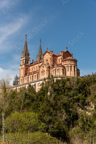 Impressive panoramic view of the touristic basilica of Santa María la Real de Covadonga built of red stone on a hill in the foothills of the Picos de Europa in Asturias
