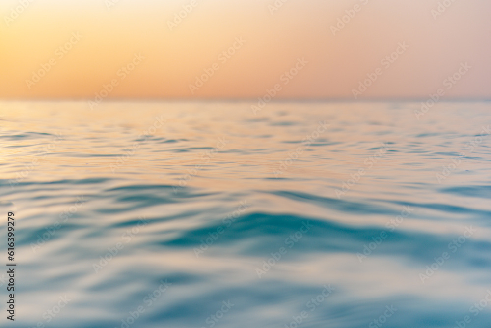 Obraz premium Beautiful closeup sea water surface. Sunset sunrise gold blue colors calm soft waves relaxing horizon. Dream fantasy shallow focus, blur seascape sky. Tranquil peaceful nature pattern, Mediterranean
