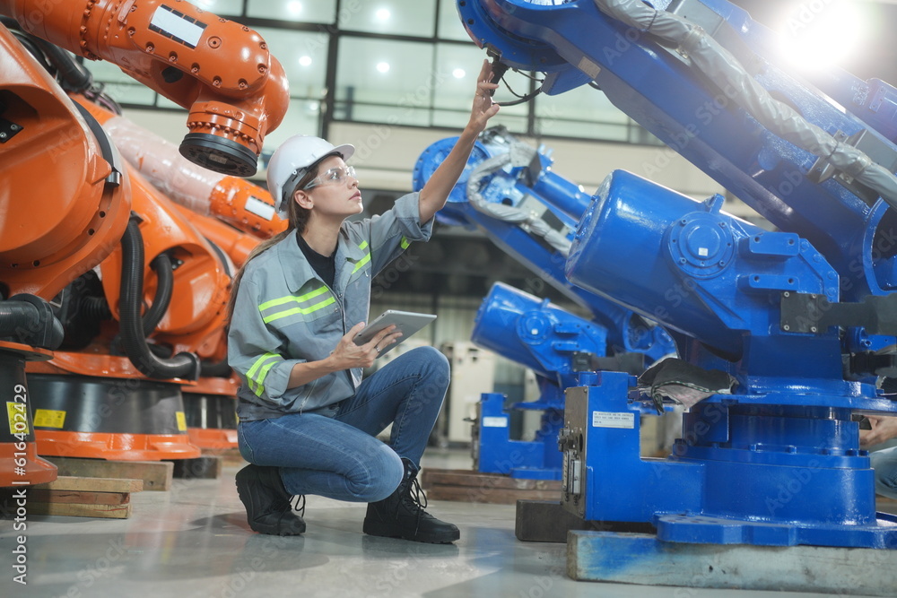 Fototapeta premium Mechanical engineers with robotic welder., Programming development technology work. Female industrial engineer working at automated AI robotic production factory