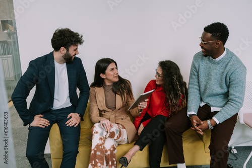 Stylish brunette businesswoman talking to her black male colleague while still laughing