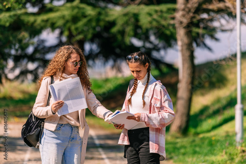 School girls standing on a road and looking for book