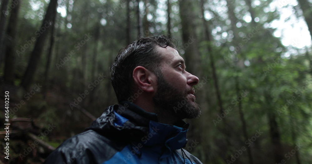 Close-up portrait of a young bearded man sitting in nature between forest trees and looking around. Close-up portrait of a young bearded man sitting in nature between forest trees and looking around.