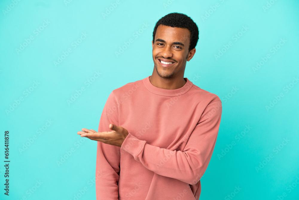 African American handsome man on isolated blue background presenting an idea while looking smiling towards African American handsome man on isolated blue background presenting an idea while looking smiling towards
