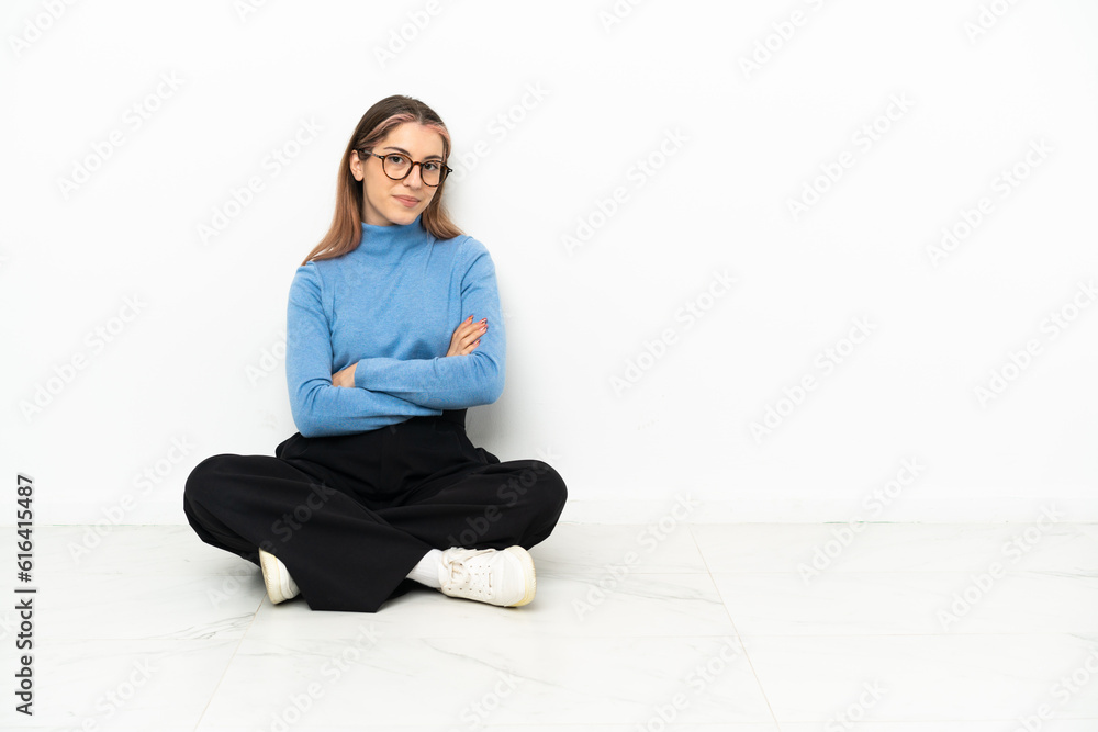 Young Caucasian woman sitting on the floor with arms crossed and looking forward Young Caucasian woman sitting on the floor with arms crossed and looking forward