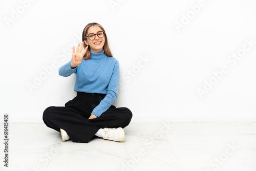 Young Caucasian woman sitting on the floor happy and counting four with fingers