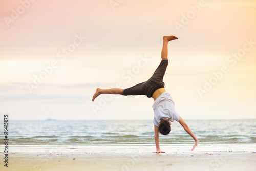 Teenager doing calisthenics exercise. Beach yoga.