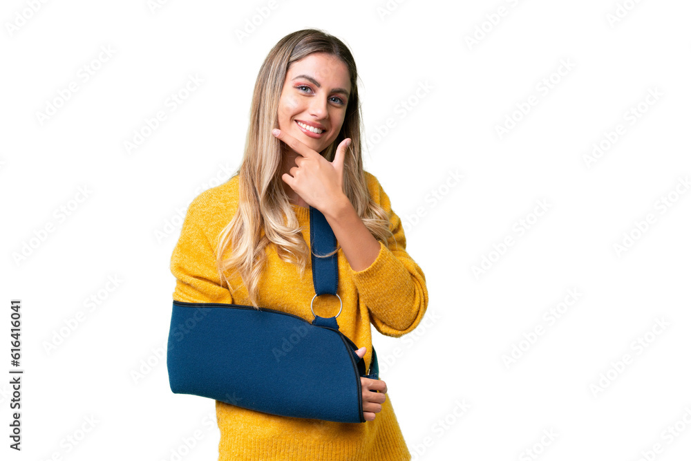 Young Uruguayan woman with broken arm and wearing a sling over isolated background happy and smiling Young Uruguayan woman with broken arm and wearing a sling over isolated background happy and smiling