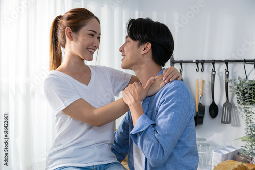 Couple playing in bed at home, hugging soft pillow, nose touching relaxed at home on bed