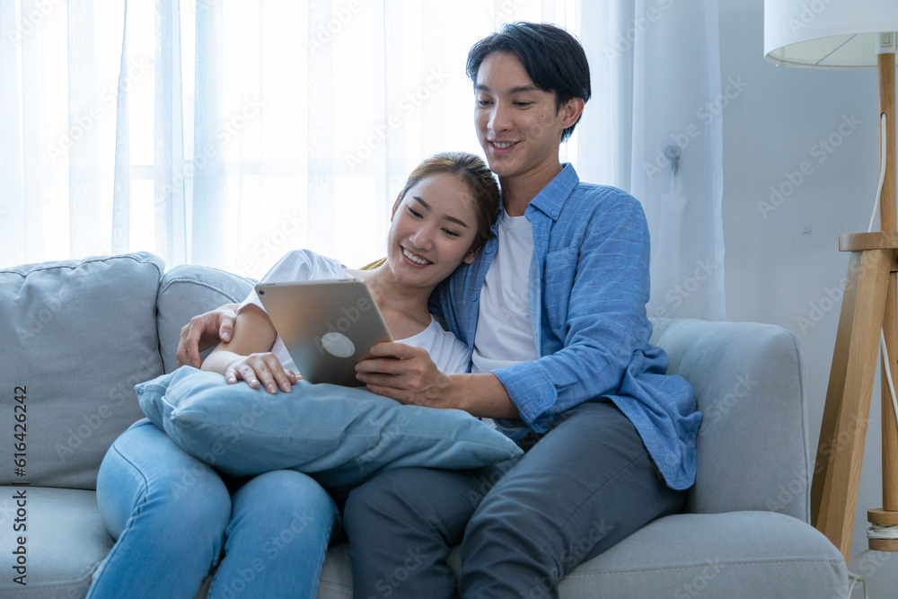 Young couple watching tv series laughing happily using tablet and sitting on sofa bed Young couple watching tv series laughing happily using tablet and sitting on sofa bed