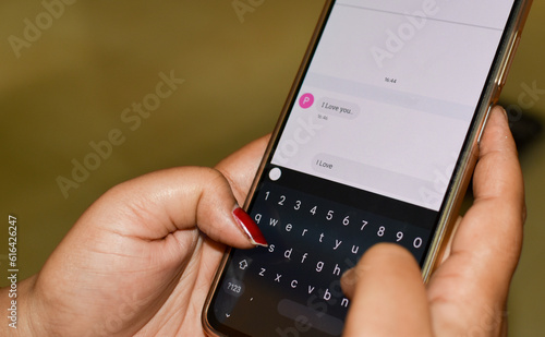 Sending I love you a text message with a mobile phone. Online dating, texting or catfishing concept. Romance fraud, scam or deceit with a smartphone. Fake profile. Internet safety.