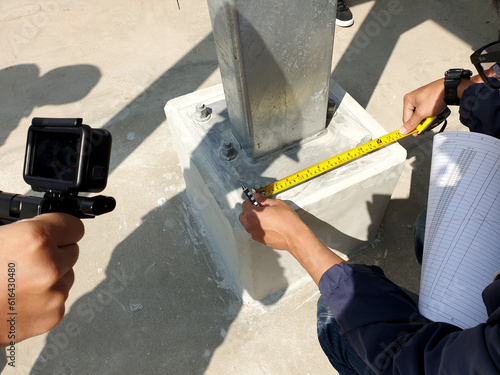 Project engineer rechecking distance of base plate connection bolts for steel structure of solar carport. photo