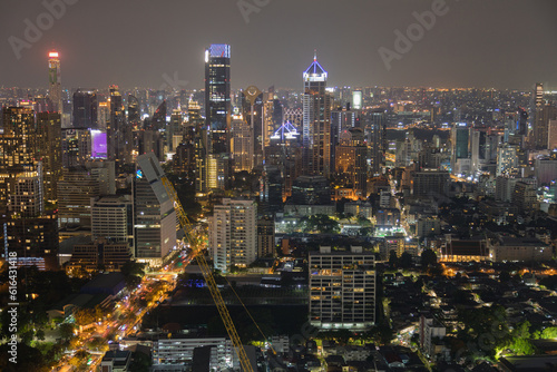 Aerial view of a large construction of a residential area with many multi-storey buildings under construction, a lot of tower cranes, workers, construction equipment at sunset 