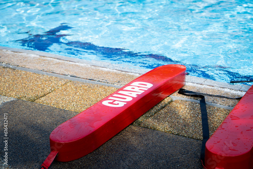 Red guard at swimming pool. Plastic tube lifesaving tool lying beside a pool. 