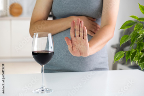 Photo Pregnant woman show NO gesture to glass of wine