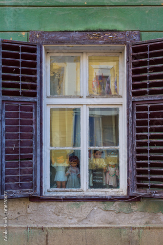 Vintage dolls in an old wooden window on the street of Sibiu. Transylvania. Romania