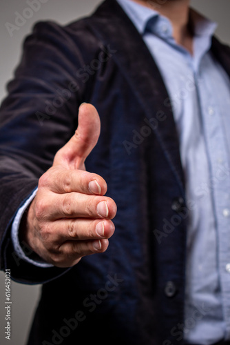 Hombre elegante dando la mano a cámara en expresión de saludo y acuerdo photo