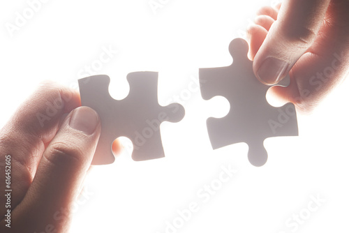 Puzzle, synergy and solution with hands of person on white background for achievement, goal and development. Mission, game and cooperation with jigsaw pieces for support, success and integration