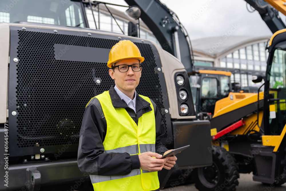 Engineer with tablet computer stands next to mining truck. Engineer with tablet computer stands next to mining truck.