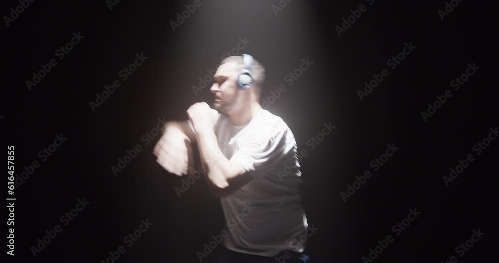 Young Caucasian male dancer in headphones dancing in darkness Young Caucasian male dancer in headphones dancing in darkness